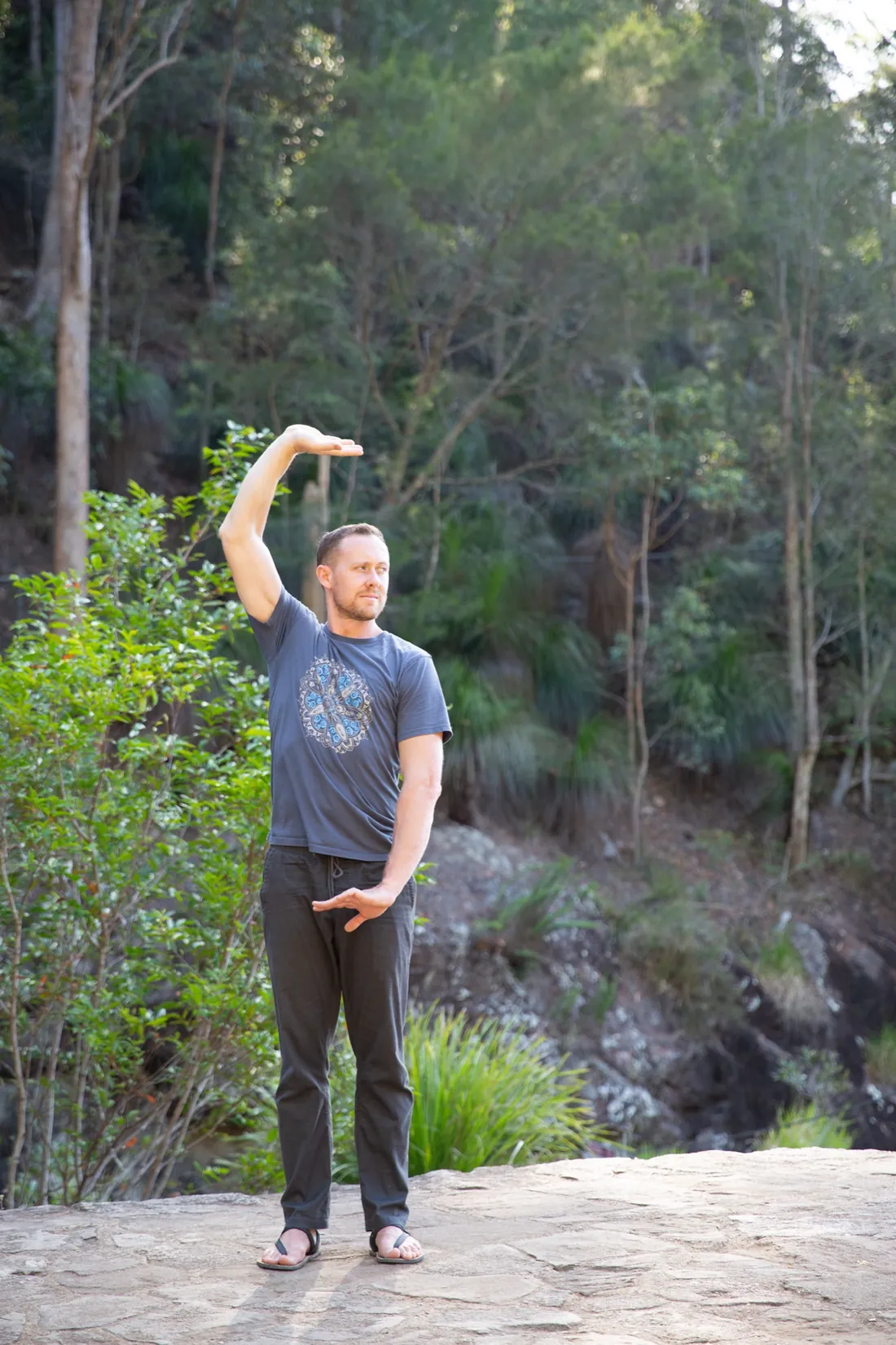 Ross Parkinson, single arm raised, bush backdrop